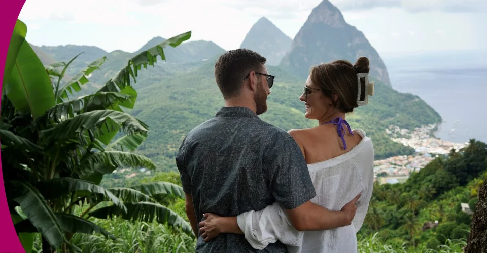 a man and woman sitting on a hill overlooking a body of water