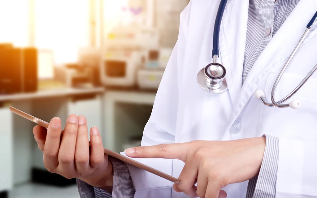 Steteskop ve tablet tutan bir doktor